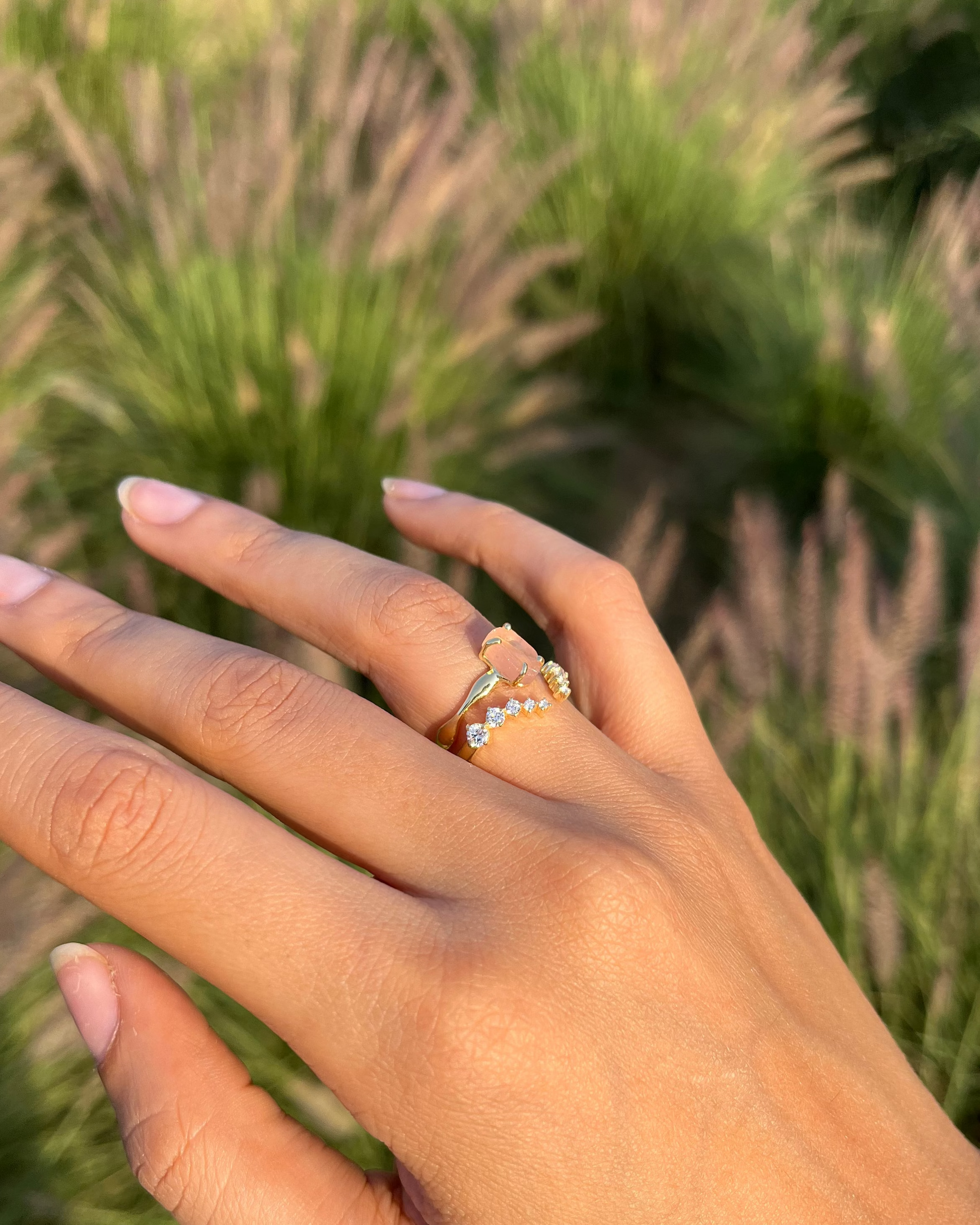 Hand wearing a ring with a grassy background